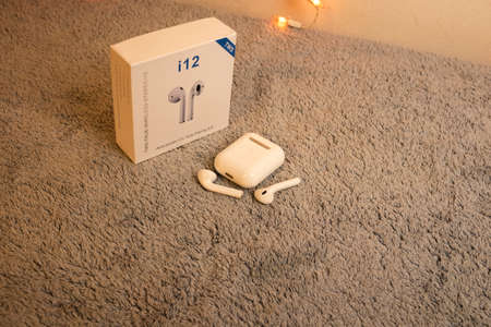 cute white wireless earbuds with charging case on a gray plush backgroundのeditorial素材