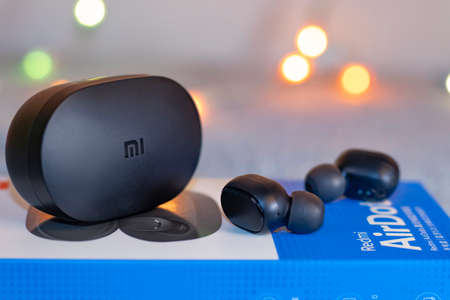 cute black wireless headphones with charging case on a gray plush background