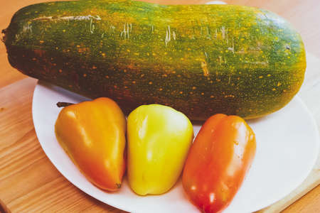 White plate on the table with fresh real peppers.