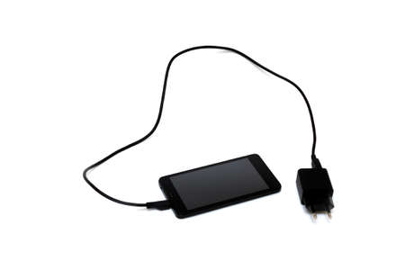 Black smartphone on an isolated white background, provd usb, the power supply is connected to the phone via a usb wire. Concept of charging phone, replenishing energyの写真素材