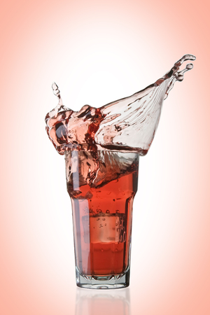 Cocktail splash with ice cube on pink background. Perfect for barの写真素材