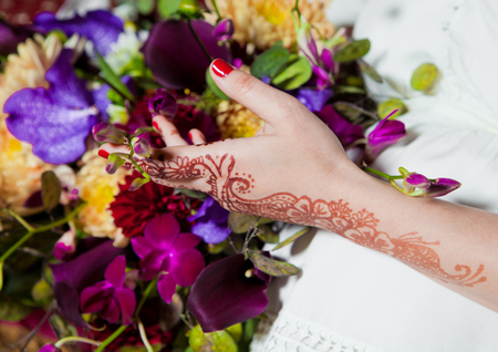 Henna tattoo on hands holding colorful flowers mixの写真素材