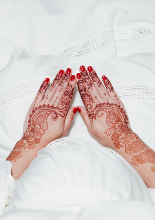 Girl is holding hands with henna tattos on white dressの写真素材
