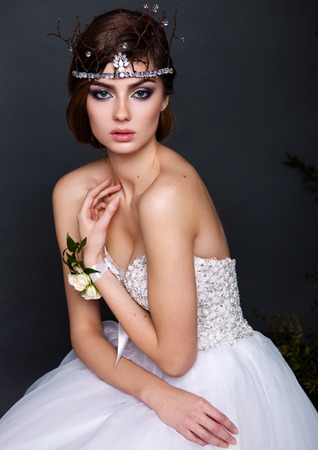 Young bride woman in wedding dress on grey background in the studio with make up and hairstyleの写真素材