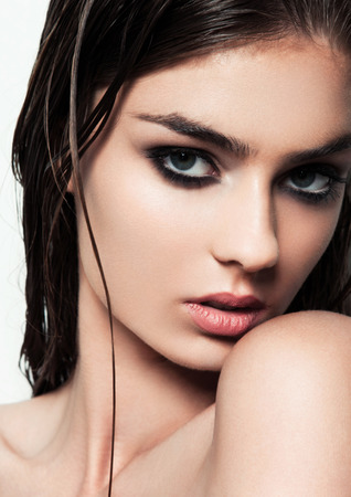 Beautiful woman with make up and wet hair on white background with smokey eyes and red lipsの写真素材