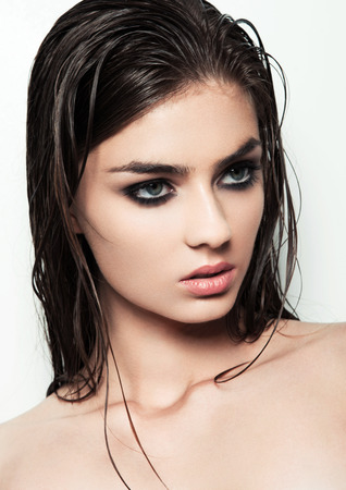 Beautiful woman with make up and wet hair on white background with smokey eyes and red lipsの写真素材