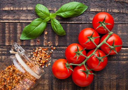 Fresh tomatoes with basiland spices jar on grunge wooden backgroundの写真素材