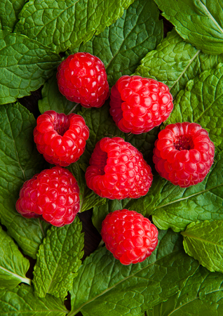 Raspberries on mint leaves clos up. Natural healthy food. Still life photography