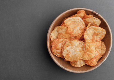 Bowl with potato crisps chips on black stone board. Junk foodの写真素材