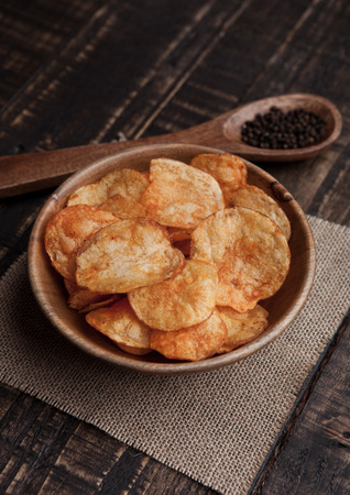 Bowl with potato crisps chips with pepper on wood. Potatoes and pepperの写真素材