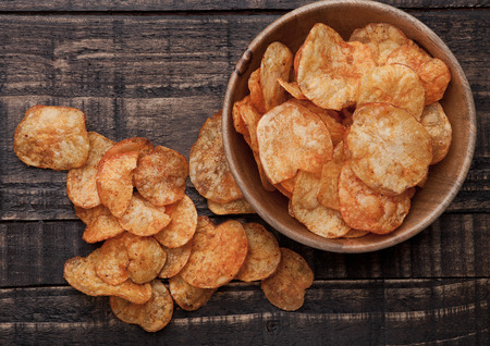 Bowl with potato crisps chips on wooden board. Junk foodの写真素材