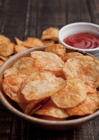 Bowl with potato crisps chips and ketchup on wooden board. Junk foodの写真素材