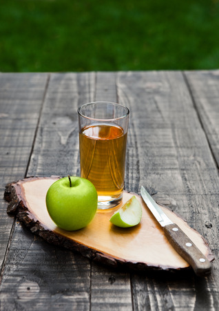 Apple juice glass with healthy green apples on kitchen board. Outside in gardenの写真素材