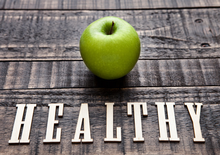 Green organic healthy apple on wooden board. With letters belowの写真素材