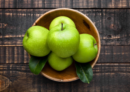 Green organic healthy apples in bowl on wooden board. Healthy foodの写真素材