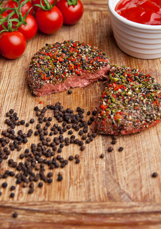 Beef raw steak with pepper and tomatoes on wooden board and  wooden background with ketchupの写真素材