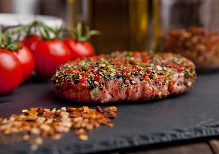 Beef raw steak with pepper and tomatoes on stone board and  wooden background with ketchupの写真素材