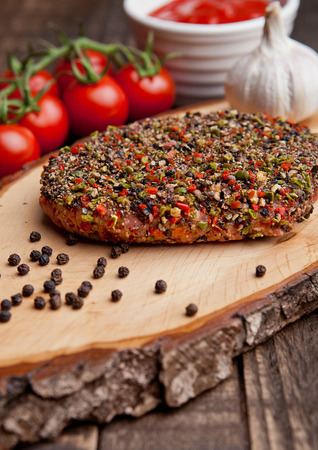 Beef raw steak with pepper and tomatoes on stone board and  wooden background with ketchupの写真素材