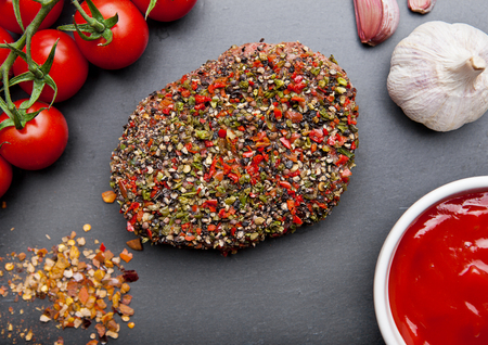 Beef raw steak with pepper and tomatoes on stone board and  wooden background with ketchupの写真素材