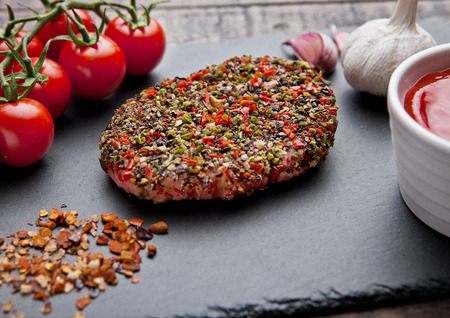 Beef raw steak with pepper and tomatoes on stone board and  wooden background with ketchupの写真素材