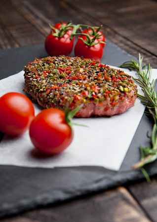 Beef raw steak with pepper and tomatoes on stone board and  wooden backgroundの写真素材
