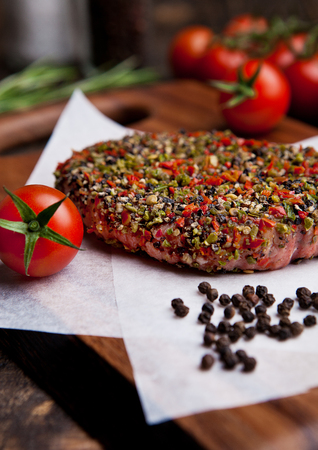 Beef raw steak with pepper and tomatoes on wooden backgroundの写真素材