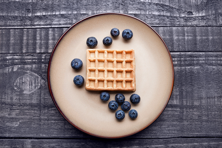 Blueberries  and sweet waffles on plate and blue wood. Still lifeの写真素材