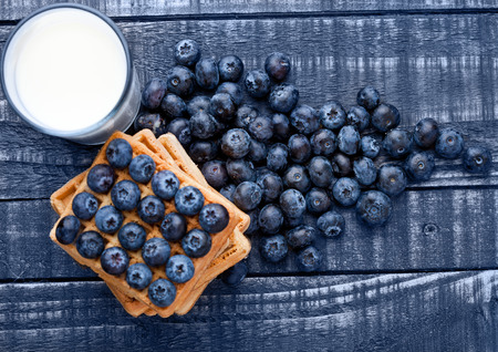 Blueberries and waffles on blue wood with milk glass. Still lifeの写真素材