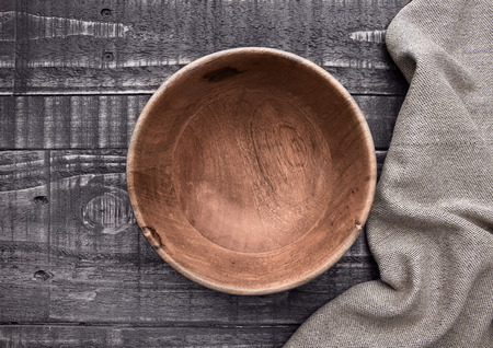 Old wooden brown bowl with kitchen cloth on wooden backgroundの写真素材