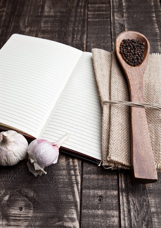 Notebook with pepper on spoon and kitchen towel on wooden boardの写真素材