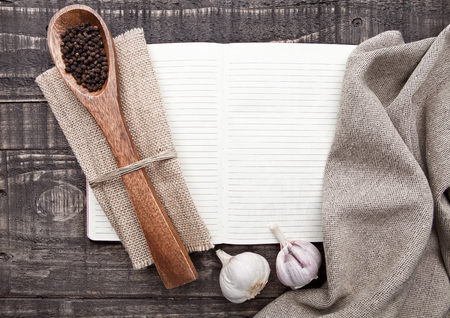 Notebook with pepper on spoon and kitchen towel on wooden boardの写真素材