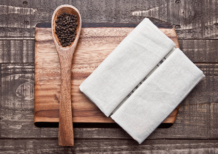 Pepper on spoon and kitchen towel on wooden board. Place for textの写真素材