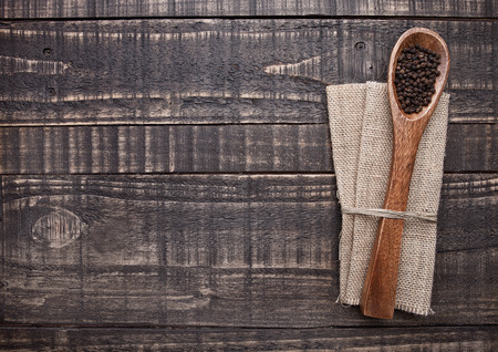 Pepper on spoon and kitchen towel on wooden board. Place for textの写真素材