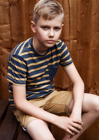 Portrait of handsome teenage happy boy outdoor in backyard.Brown wood backgroundの写真素材