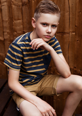 Portrait of handsome teenage happy boy outdoor in backyard.Brown wood backgroundの写真素材