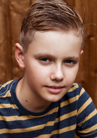 Portrait of handsome teenage happy boy outdoor in backyard.Brown wood backgroundの写真素材
