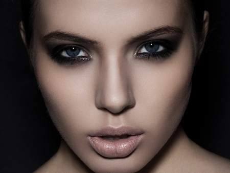 Beautiful woman model smokey eyes makeup close up on black backgroundの写真素材