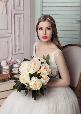 Beautiful young bride with flowers  romantic decoration pink and green. Wooden boxes bottles and different wedding decorationの写真素材