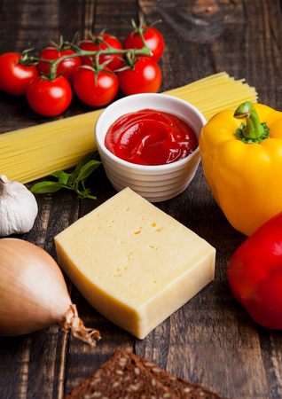 Raw food mix spaghetti tomatoes cheese and bread on wooden tableの写真素材