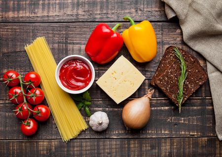 Raw food mix spaghetti tomatoes cheese and bread on wooden tableの写真素材