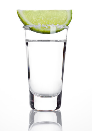 Silver tequila shot glass with lime slice and salt on white backgroundの写真素材