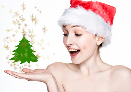 Beautiful woman happy christmas in santa hat holding christmas tree on arm with golden stars on white backgroundの写真素材
