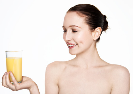 Beautiful woman holding glass with orange juice with white top on white backgroundの写真素材