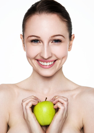 Beautiful fitness woman holding healthy apple on white backgroundの写真素材