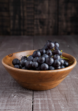Fresh healthy grapes in wooden bowl on wooden backgroundの写真素材