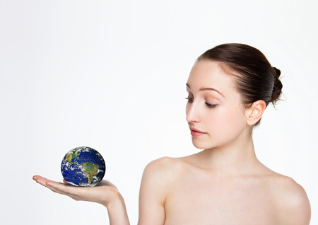 Beautiful woman holding earth globe on her arm on white backgroundの写真素材