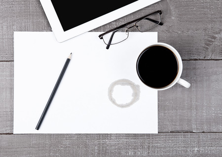 Graphic tablet with glasses paper sheet and coffee on office deskの写真素材