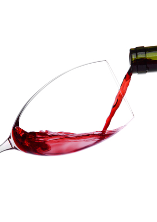 Pouring red wine from bottle to glass isolated on white backgroundの写真素材