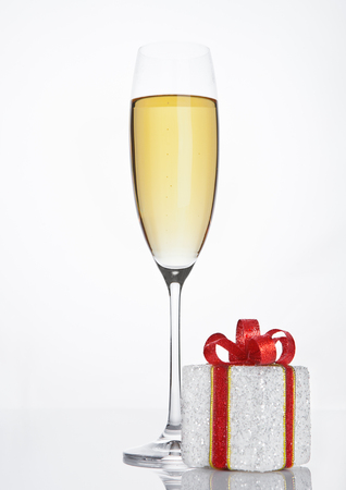 Glass of sparkling champagne with red gift box on white backgroundの写真素材