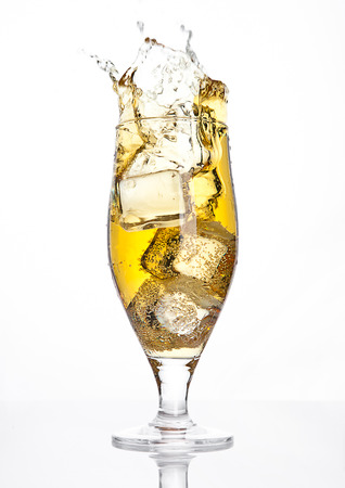 Glass of beer cider with ice cube splash on white backgroundの写真素材